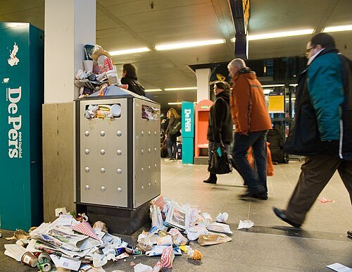 An overflowing bin with litter on the floor