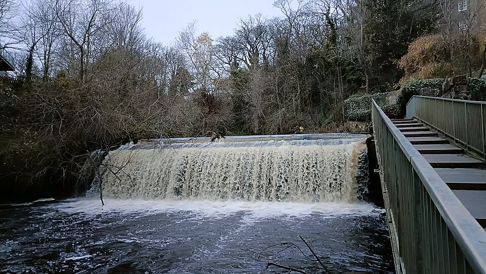 A weir: a low dam across a river, with water flowing evenly over its crest