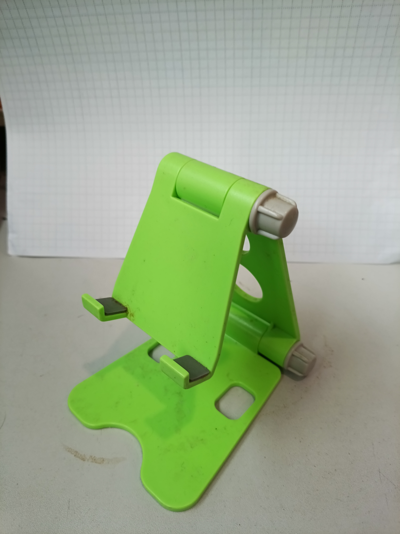 Green phone stand on a pale surface, source photograph